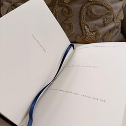 Open book with a blue ribbon bookmark showing examples of the questions within the book
